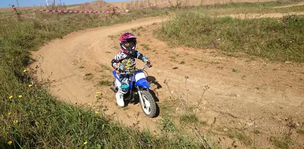 Kleines Kind mit pinkem Helm fährt durch eine Kurve der Kinderstrecke